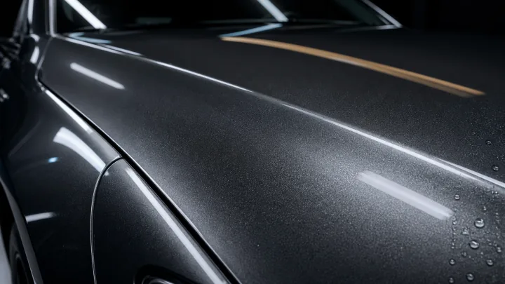 Illustrative graphite automotive paint surface with a muted, unfinished appearance.