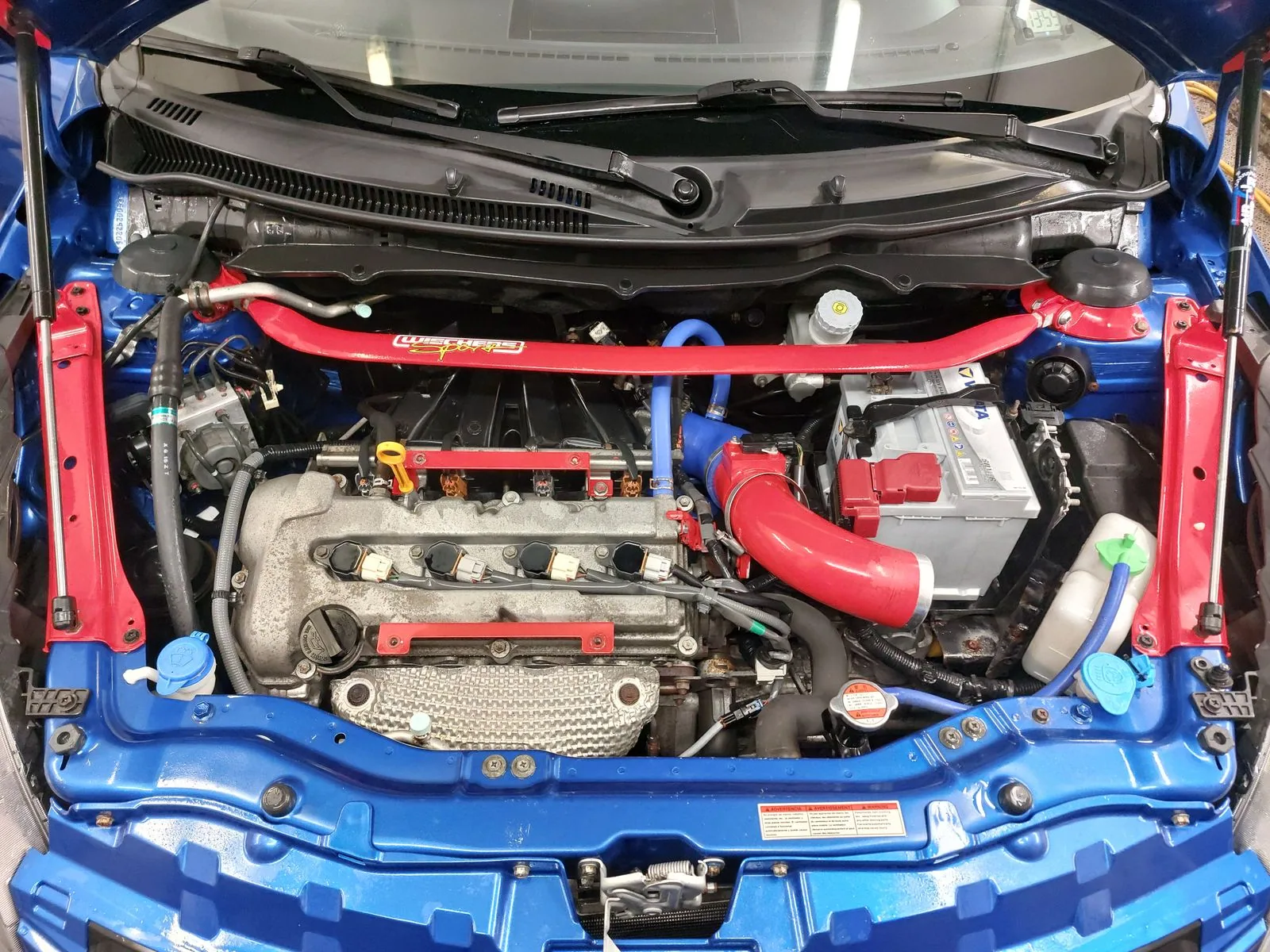 The same engine bay after washing, with cleaned components and surfaces.
